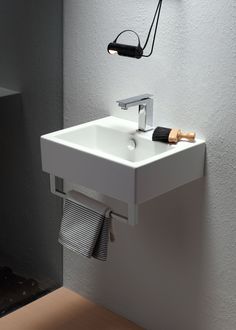 a white sink sitting next to a wall mounted faucet