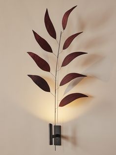 a wall mounted light with a metal plant on it's side and two lights behind it