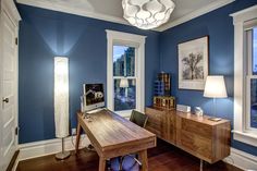 a room with blue walls and wooden furniture in the center is lit by a white chandelier