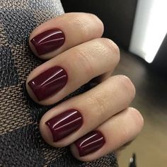 a woman's hand with a maroon manicure on top of her nail polish