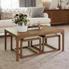 a living room filled with furniture and flowers on top of a coffee table in front of a window