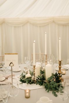 the table is set with candles and greenery