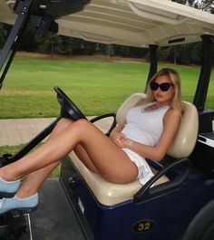 a woman is sitting in the back of a golf cart with her legs spread out