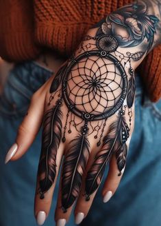 a woman's hand with a tattoo on it and a dream catcher in the middle