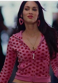 a woman in pink shirt and black shorts with heart shaped hoop earrings on her head