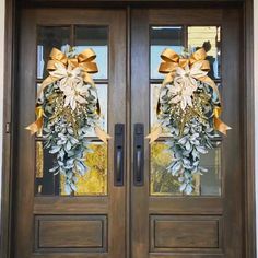 two brown double doors with wreaths on them and gold ribbons hanging from the side