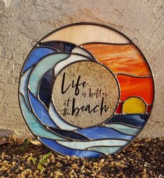 a stained glass plate with the words life is but at beach