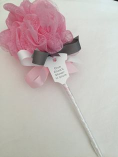 a pink flower on top of a white table with a name tag attached to it