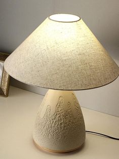 a white lamp sitting on top of a table next to a framed photo and clock