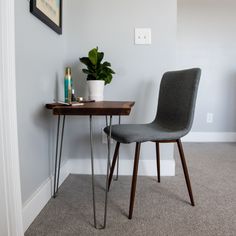 a gray chair sitting next to a table with a potted plant on top of it