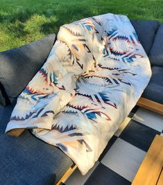 a blanket is laying on top of an outdoor couch in the grass near a grassy area