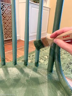 someone is painting the back of a chair with green paint and a brush in their hand