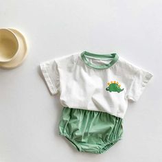 a white shirt and green shorts are sitting next to a coffee cup on a table