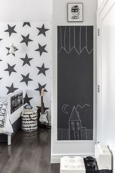 a bedroom with black and white stars painted on the wall next to a chalkboard