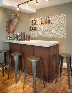 a bar with three stools and a deer head mounted on the wall above it