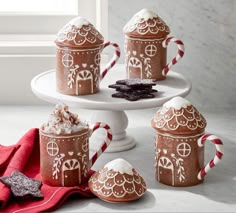 gingerbread mugs decorated with white icing and candy canes on a cake stand