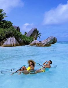 two people in a body of water with paddles on their backs and one person laying down