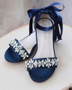 a pair of blue high heeled shoes with flowers on the side and a bow