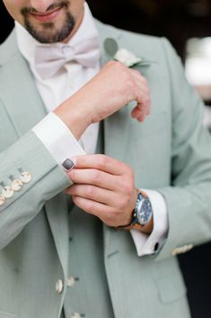 a close up of a person wearing a suit and holding a flower in his hand