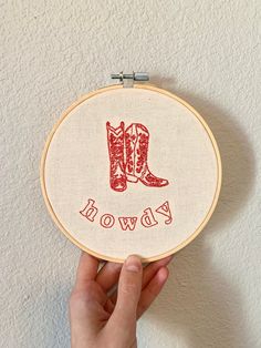 someone is holding up a cross stitched cowboy boot with the word cowboy on it