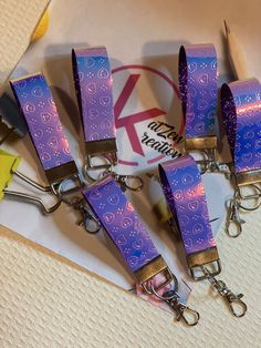 six purple and gold lanyards with matching keychains on top of each other