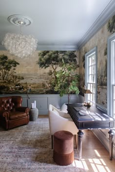 a living room filled with furniture and a painting on the wall behind a desk in front of a window