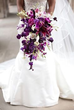 the bride is holding her purple and white bouquet