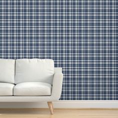 a white couch sitting in front of a blue plaid wall