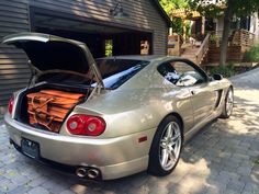 a silver sports car parked in front of a garage with its hood open and it's engine exposed