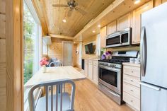 a kitchen with wooden walls and flooring has stainless steel appliances