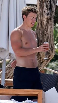 a shirtless man holding a drink in his hand