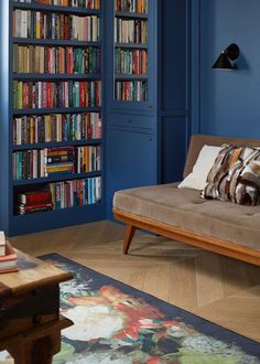 a living room with blue walls and bookshelves in the corner, including a couch