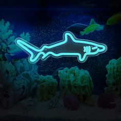 a neon sign in the shape of a shark swimming over corals and seaweed