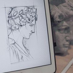 a drawing of a woman's head is shown on a tablet screen next to some statues