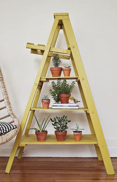 a wooden shelf with potted plants on it next to a wicker rocking chair