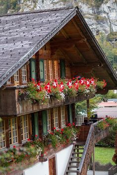 a house with flower boxes on the balcony and stairs leading up to it's second floor