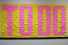 a bulletin board covered in pink and yellow post - it notes on a white wall