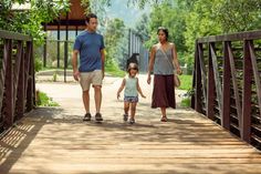 a family walking across a bridge in the park