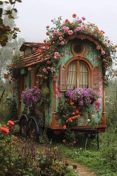 a small house with flowers growing on the roof and windows is shown in this photo