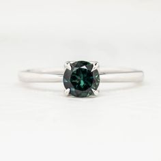 * One of a kind ring * In stock ready to ship in size 7 * 0.82ct Teal Blue Green Queensland Sapphire, 5.67x5.67x3.31mm, vvs, very clean with no visible inclusions even with a 10x magnification * Band width: approx. 1.6-1.8mm * High profile four prongs flower setting for easy stacking * Made of recycled solid 14k white gold and ethically sourced gemstones * Packaged in a recyclable kraft ivory ring box Modern Emerald Round Rings, Timeless Green Sterling Silver Ring, Emerald Ring With Vvs Clarity Round Cut, Modern Round Emerald Rings, Green Platinum Ring With Round Cut, 14k White Gold Emerald Promise Ring, Sterling Silver Rings With Brilliant Cut For May Birthstone, Sterling Silver Brilliant Cut Rings For May Birthstone, Green Platinum Rings For Gifts