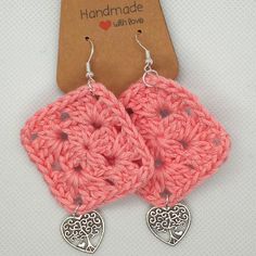 pink crochet earrings with heart shaped dangles on top of a white table