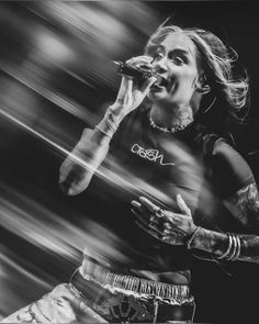 a black and white photo of a woman singing into a microphone