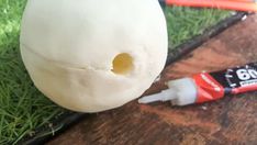 a white ball sitting on top of a wooden table next to a tube of toothpaste