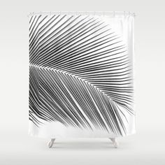 a white shower curtain with black and white palm leaf print on it's side