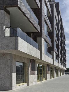 an empty parking lot in front of a tall building with balconies and windows