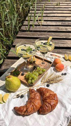 two croissants on a picnic table with fruit and wine in the background