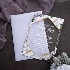 an elegant wedding card with flowers on the front and back, is laying next to a bouquet of baby's breath