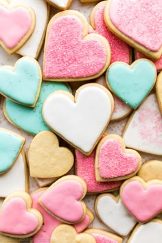 some heart shaped cookies are on a table with pink, blue and white frosting