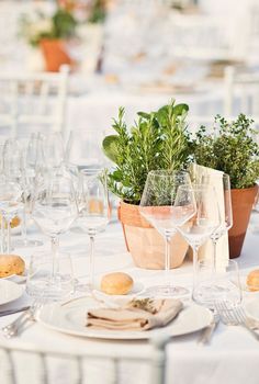 the table is set up with wine glasses and flowers in vases on each side