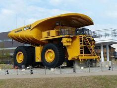 a large yellow dump truck parked in front of a building